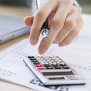 hand holding pen over a calculator